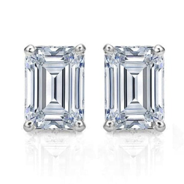 A pair of emerald cut diamond stud earrings set in a white gold band