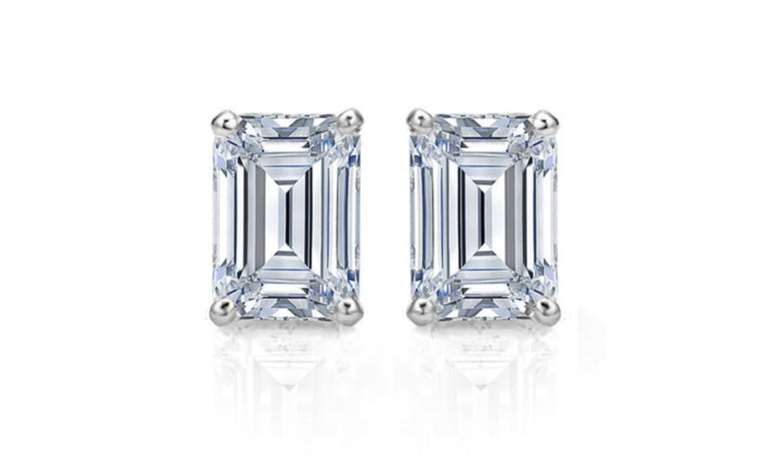 A pair of emerald cut natural diamond stud earrings with a G color and VS1 clarity, displayed against a white background.