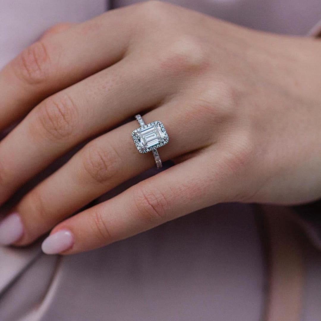 Halo emerald cut engagement ring on finger